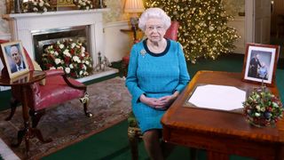 Queen Elizabeth II sits at a desk in the Regency Room after recording her Christmas Day broadcast