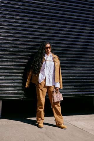 Woman at New York Fashion Week wearing a Carhartt barn jacket, white button down, cargo pants, and boots.