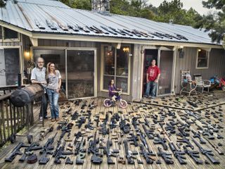 Suburban family posing on deck of house, with hundreds of guns. From the exhibition Suburbia. Building the American Dream