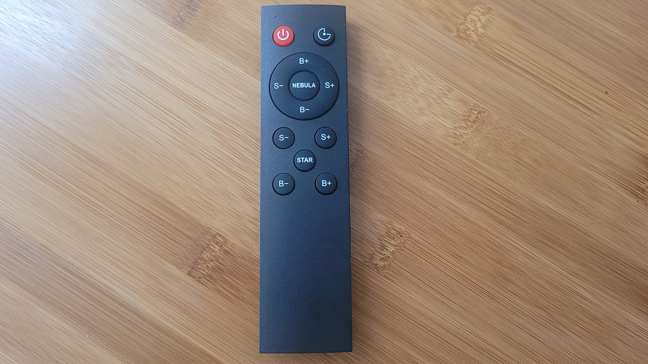 The remote control for the Astronaut Starry Sky Projector on a wooden table