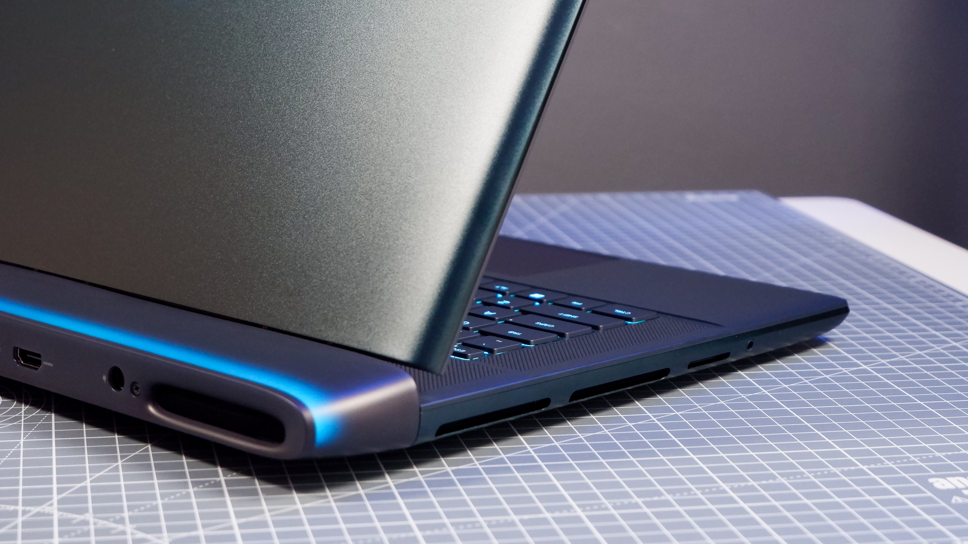 An Alienware 16 Area-51 gaming laptop with RGB lighting in blue on a desk mat.