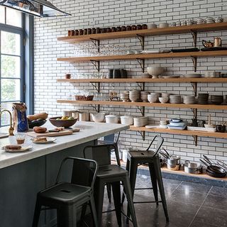 kitchen with open wooden shelf bar stools and white tiled flooring