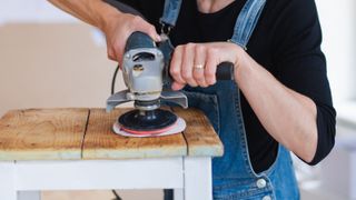 person sanding a table top with an angle grinder