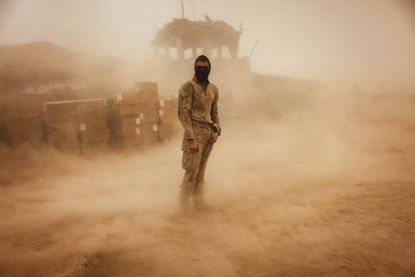 An American soldier stands in a sandstorm at his outpost in Afghanistan.