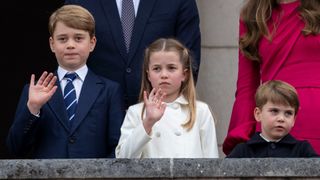 Prince George of Cambridge with Prince Louis of Cambridge and Princess Charlotte of Cambridge stand on the balcony at Buckingham Palace