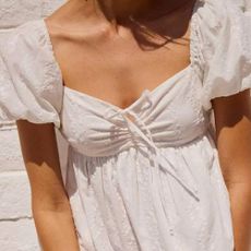 A close up of a woman wearing a white summer dress from Tillys.
