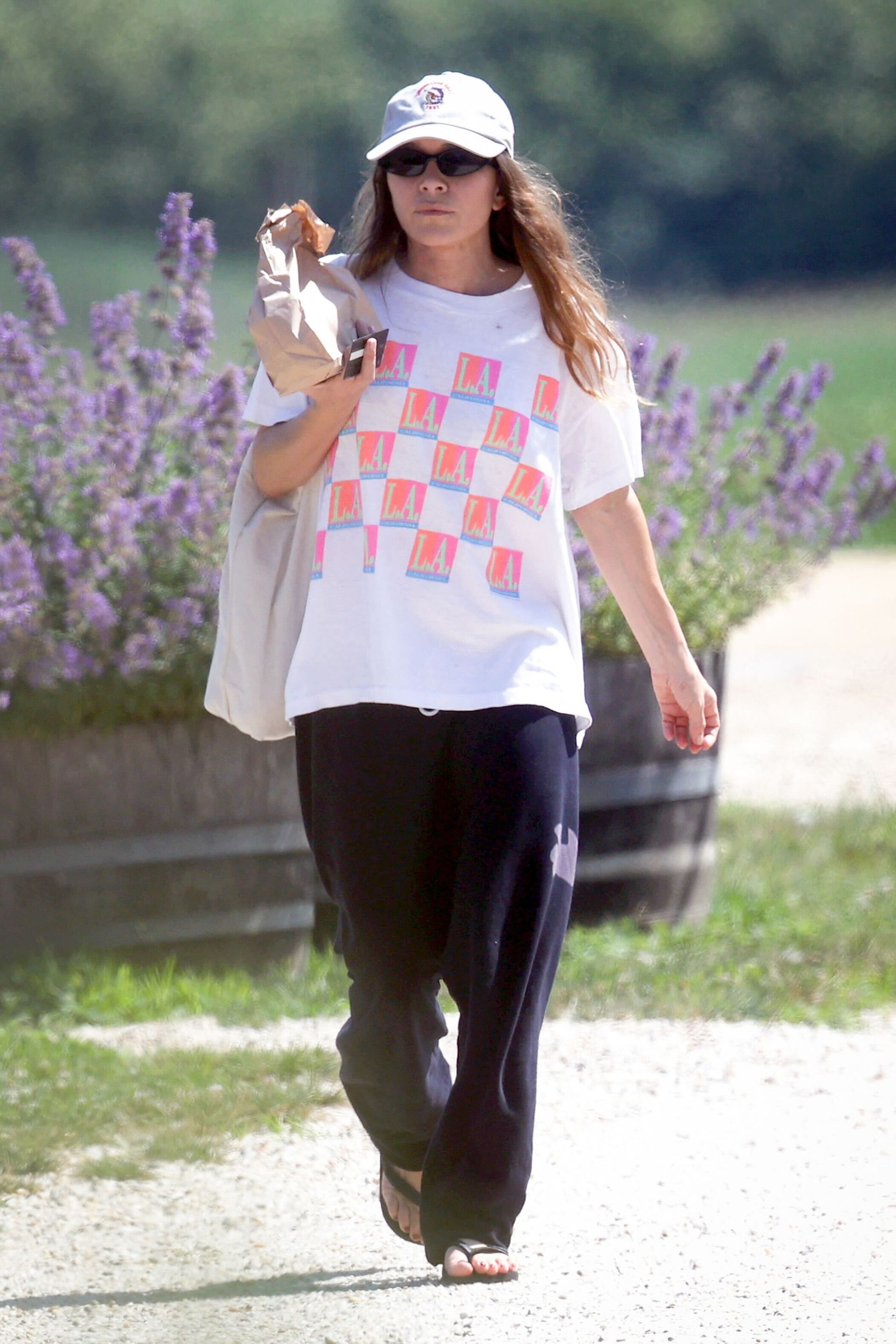 Mary Kate Olsen wears a white graphic tee, black free city sweatpants, and black flip-flops.