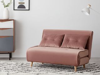 pink sofa bed in a grey living room with a brown, blue, grey and white sideboard to the left of the image