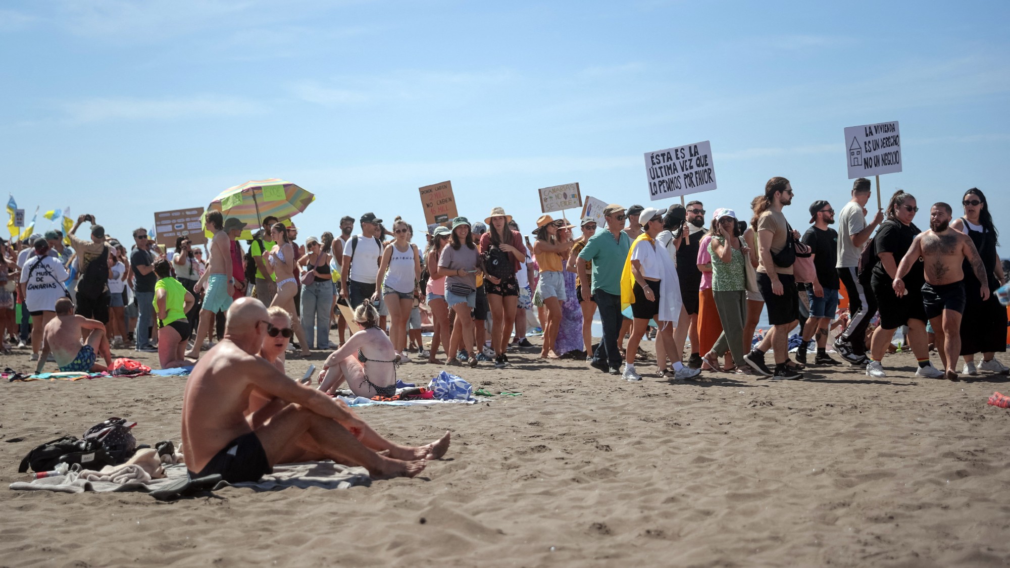Mass tourism protesters march past sunbathers on Tenerife's Las Americas beach 