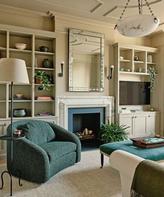 Living room with green armchair and ottoman and iron floor ligth and pendant light and cream walls