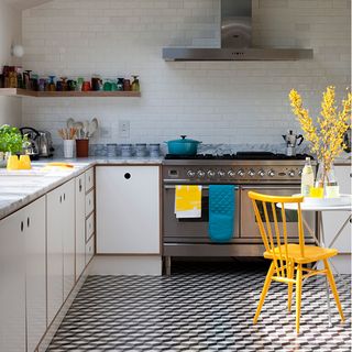 black and white kitchen with yellow stool and geometric floor tiles
