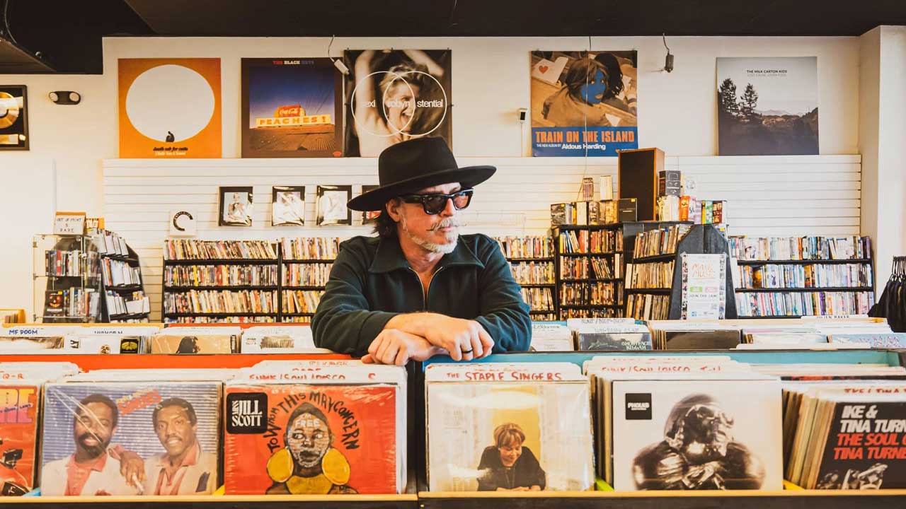 Scot Holiday leaning on the racks in a record shop