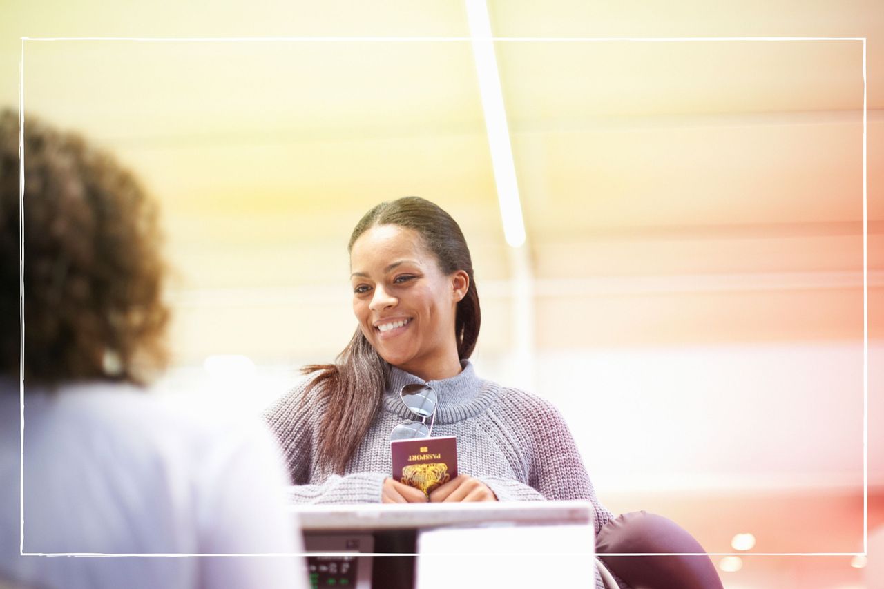 Smiling woman holding passport at airport check-in desk