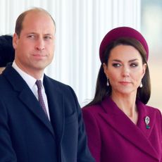 Prince William wears a suit and Kate Middleton wears a burgundy coat with matching hat