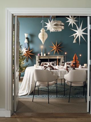 a dining table decorated for Christmas with decorative paper stars hanging above