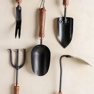 A set of Magnolia gardening tools with black scoops and wooden handles: includes a fork and scoop