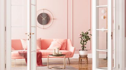 A chic pink apartment with a pink couch, open balcony doors and a pot plant.