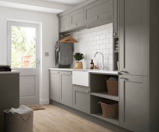 utility room with stone coloured cabinets, butler sink, cupboards and hanging rail above sink for laundry