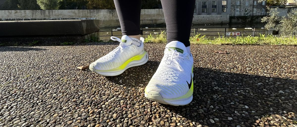 Woman&#039;s feet wearing Nike Infinity Run Flyknit 4 road running shoes - front view