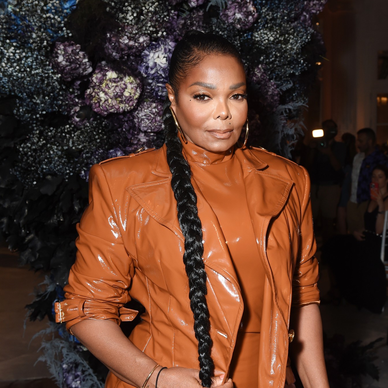 a black woman with dark hair wearing a long braid and a tan coat