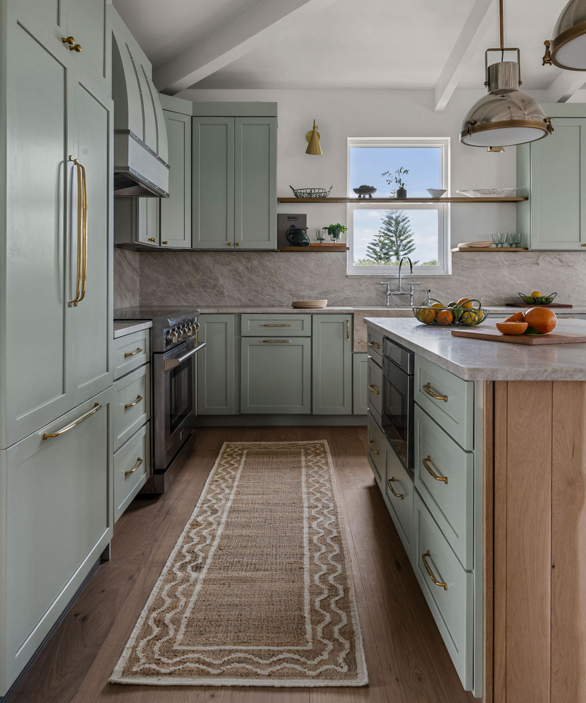 Kitchen with gray cabinets and island, area rug, range and pendant light over island