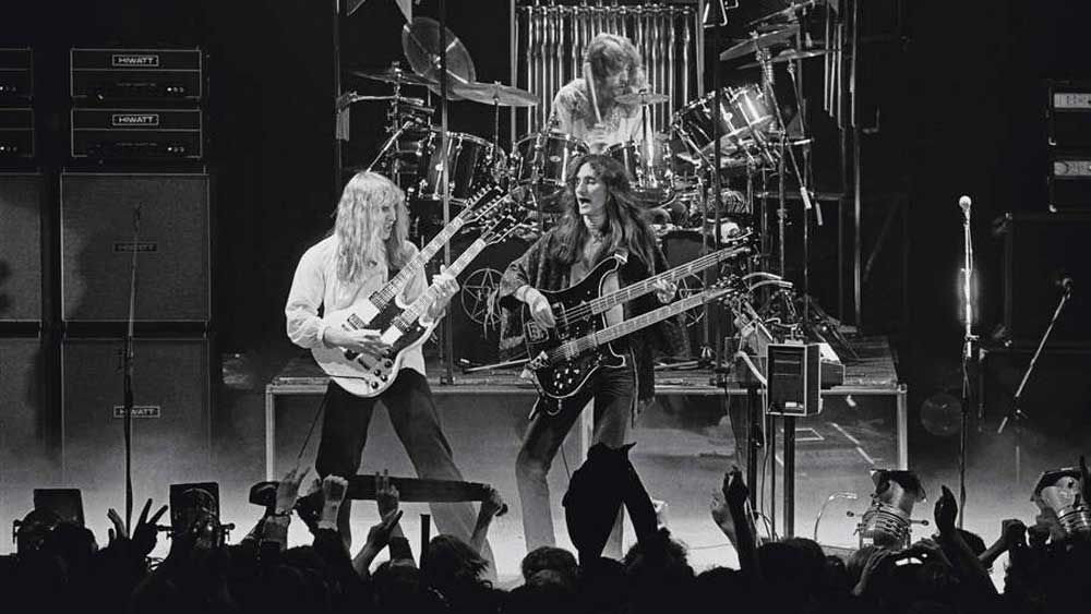 Guitarist Alex Lifeson, bassist Geddy Lee and (behind) drummer Neil Peart from Canadian progressive rock band Rush perform live on stage at the Odeon in Birmingham, England during their &#039;Farewell To Kings&#039; tour on 12th February 1978