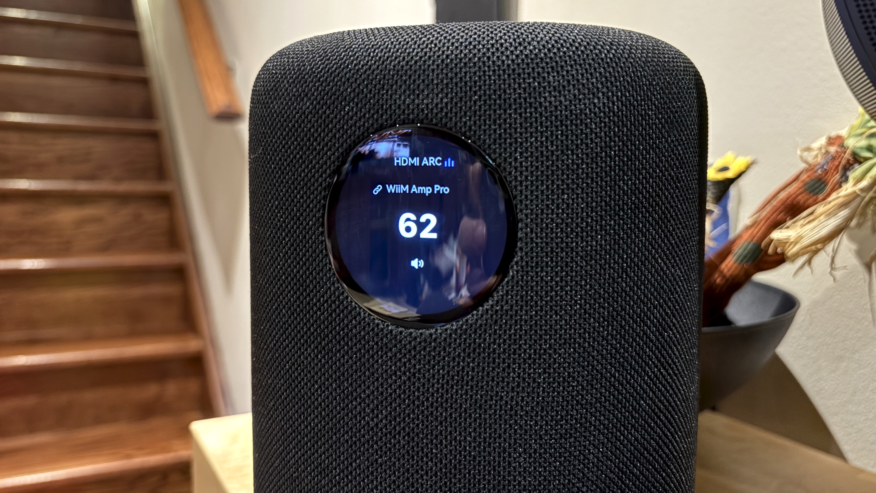 The WiiM Sound, in a home, on a varnished wooden table, showing the illuminated front panel 