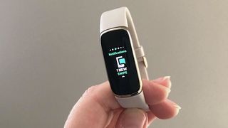 Fitbit Luxe held up by a hand to showcase notifications