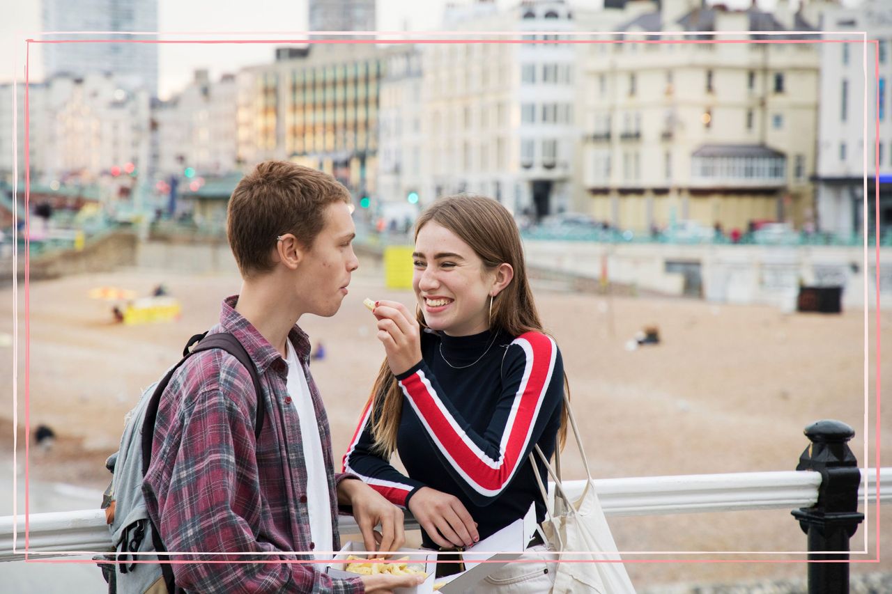 A teenage boy and girl smiling together on a pier