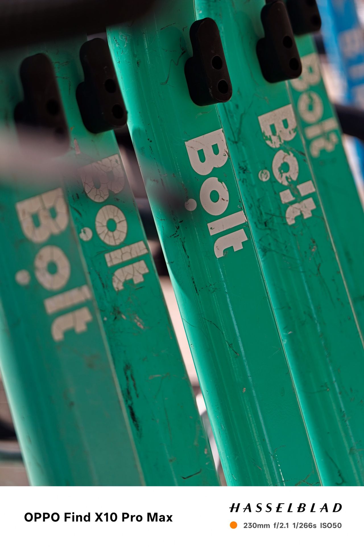 Close-up of several green Bolt rental scooters with shallow depth of field.