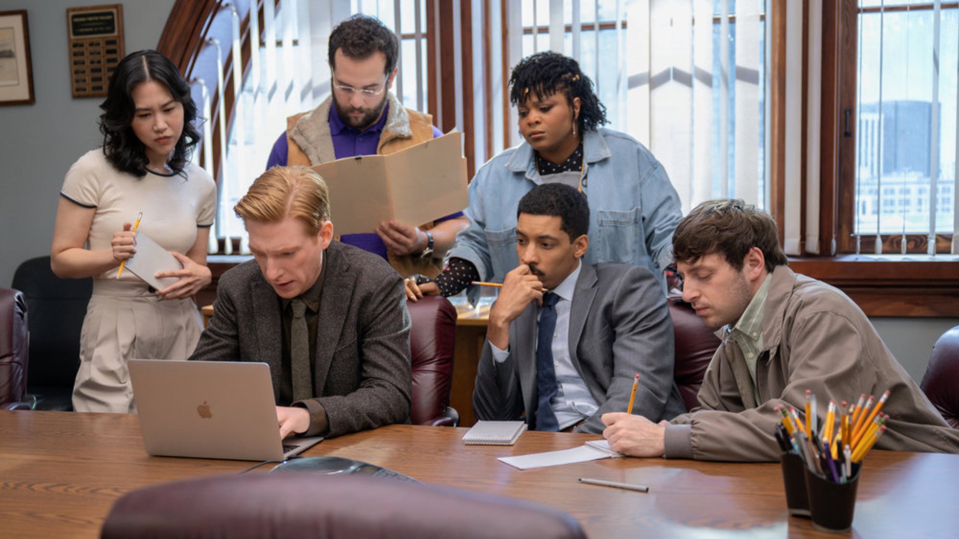 The staff gather round a laptop in The Paper season 1