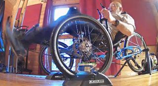 A male hand cyclist rides his handcycle indoors