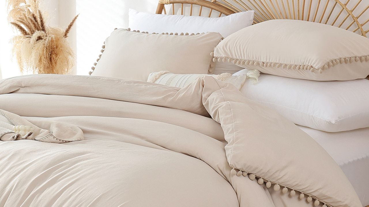 Beige bedding with pom poms on wooden bed frame