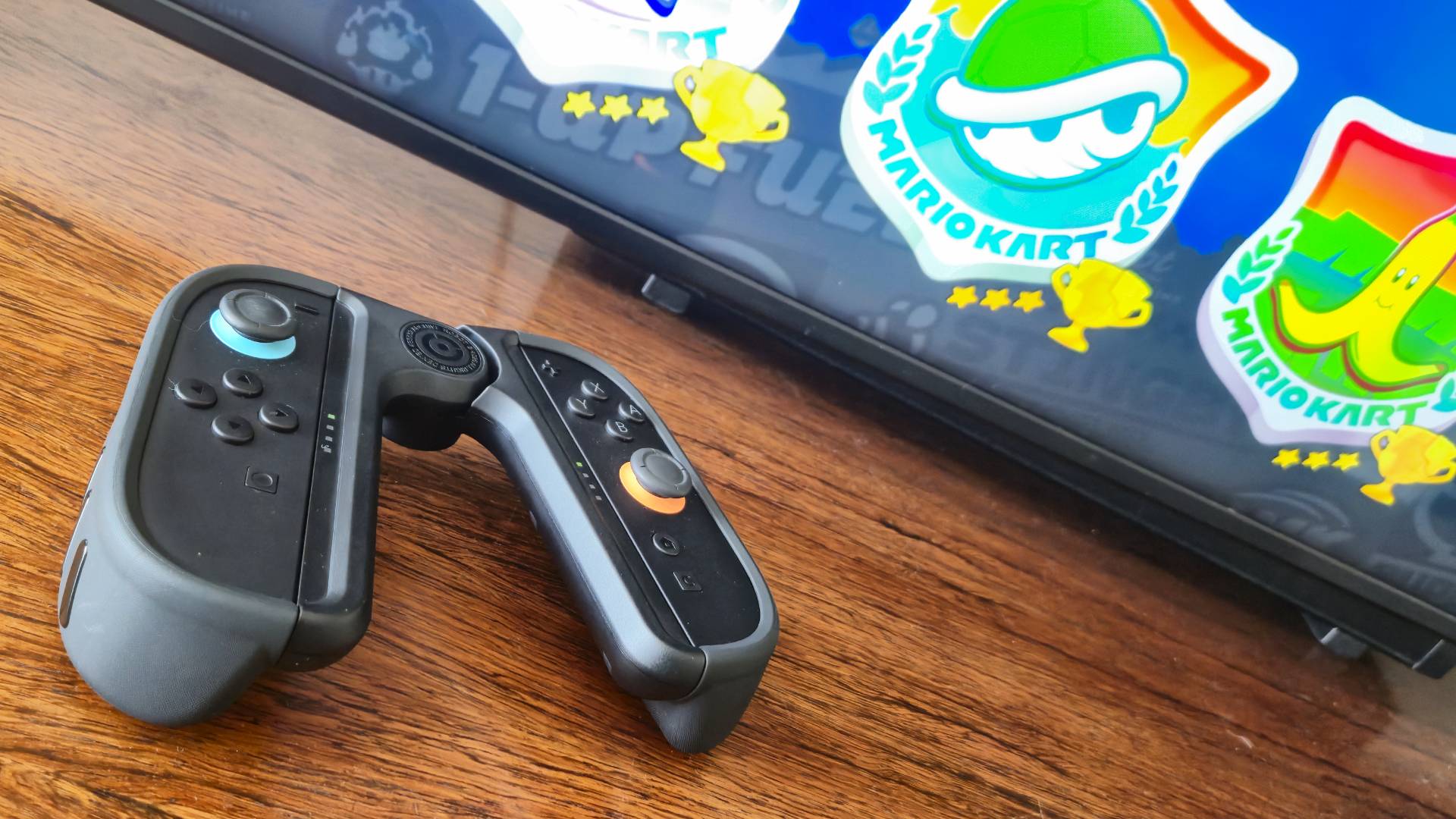 Photo of the Dbrand Joy-Lock Controller Holder sitting in front of a TV playing Mario Kart World.