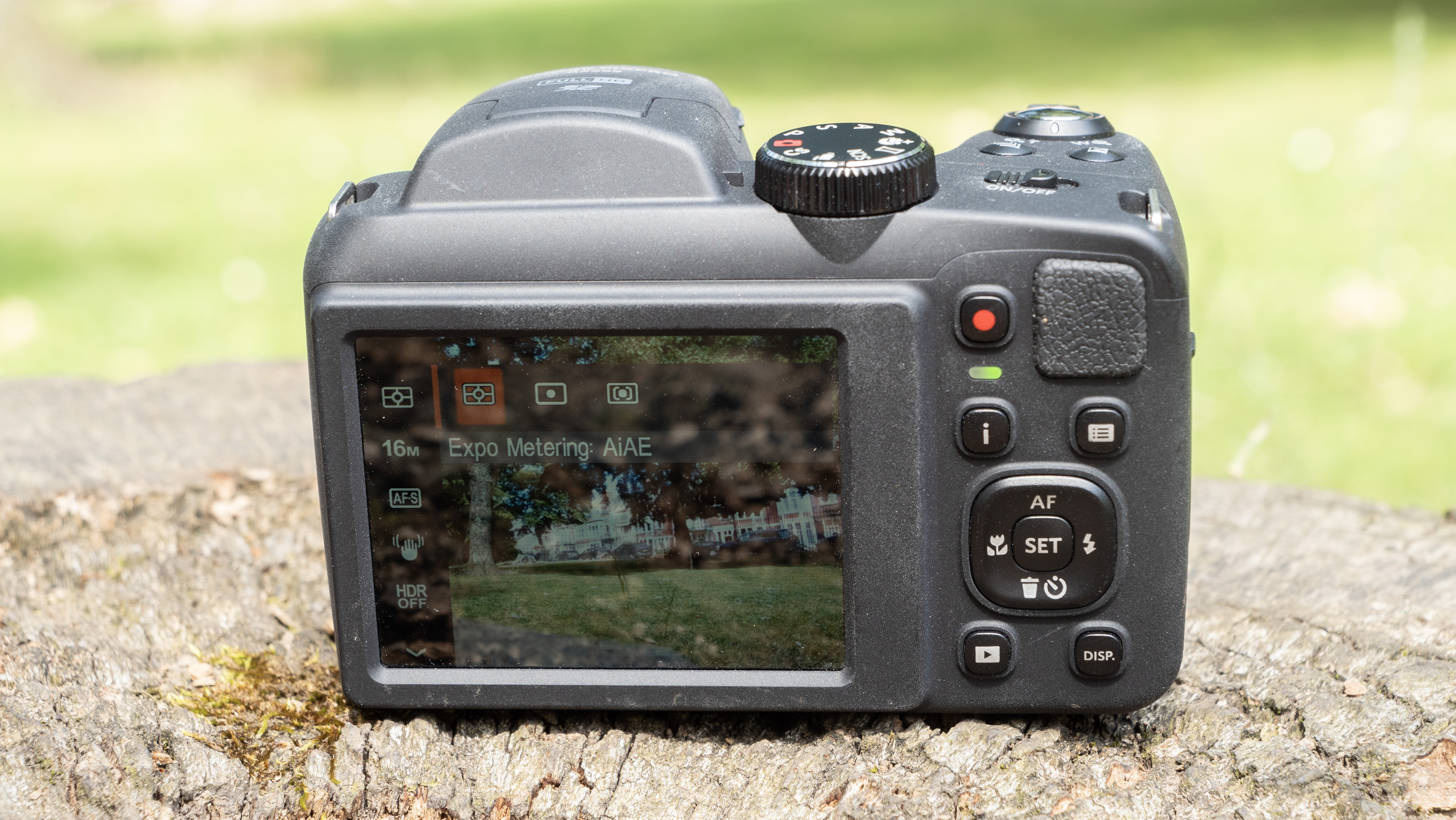 Kodak PixPro AZ255 digital camera in black on a stone surface in front of a green background outside