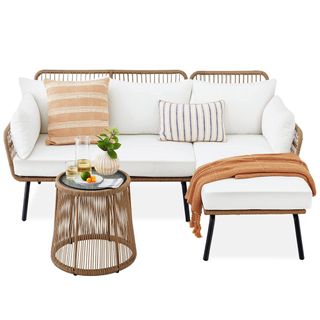 A wooden woven lounge sectional with white cushions and a woven table