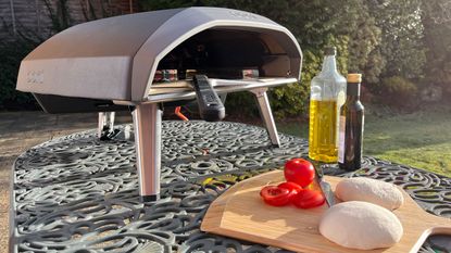 an Ooni pizza oven outdoors on a metal garden table