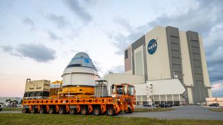 Boeing's CST-100 Starliner spacecraft passes by the Vehicle Assembly Building at NASA's Kennedy Space Center in Florida on Nov. 21, 2019, on its way to the Space Launch Complex 41 Vertical Integration Facility at Cape Canaveral Air Force Station.