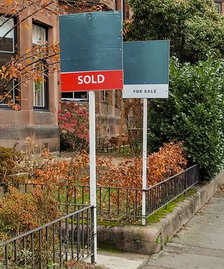 Pavement, front gardens with railings in front and terraced houses with a sold and a for sale sign