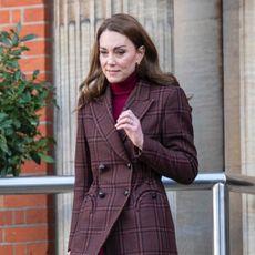 Kate Middleton wearing a brown plaid coat and burgundy turtleneck