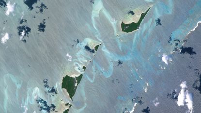 An astronaut photo of two islands in the Bahamas surrounded by twisting ribbons of shining blue sand banks