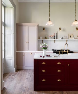 Colour contrast kitchen with pale pink cabinetry and deep red island