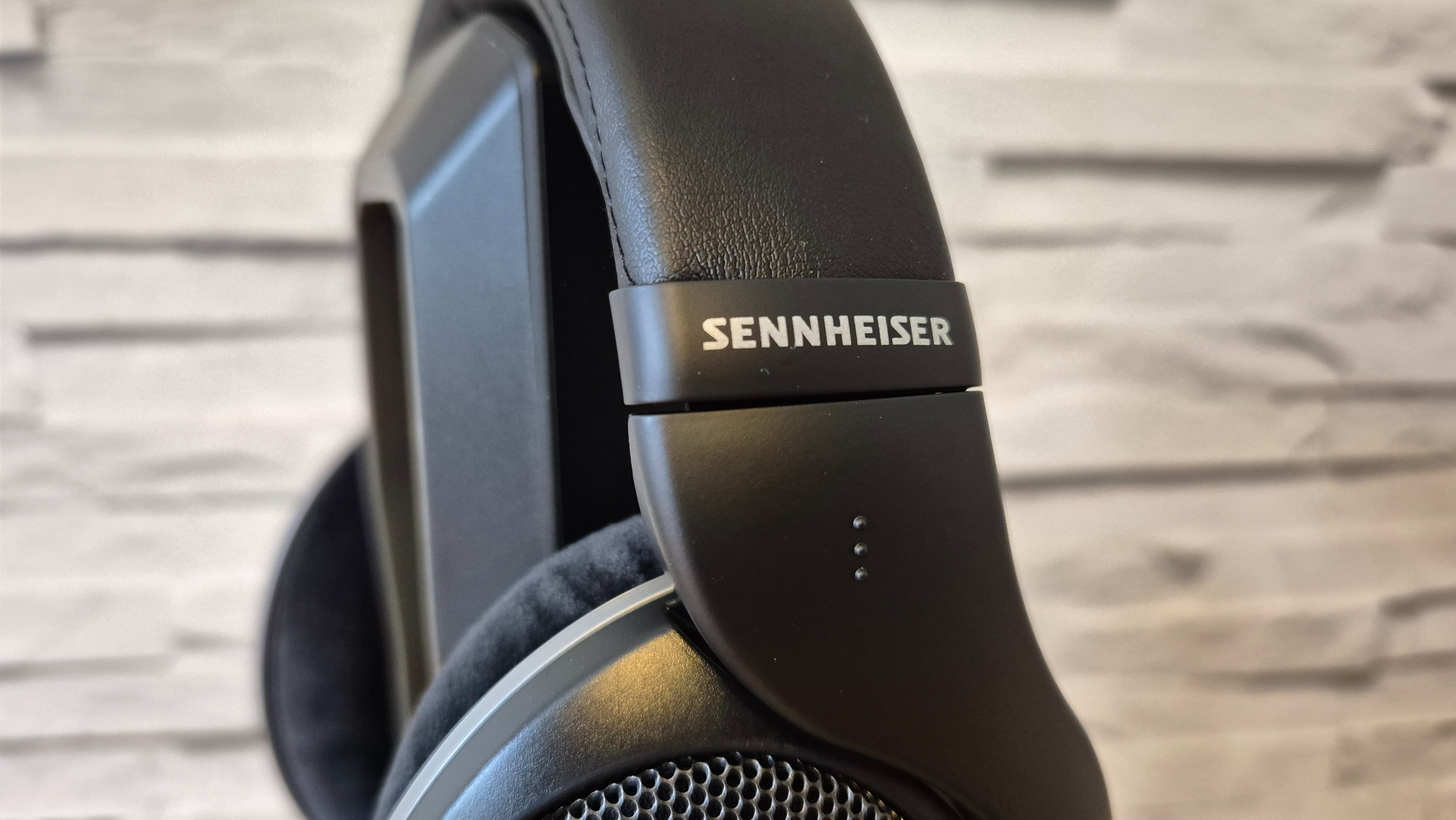 The Sennheiser HD 550 headphones on a wooden surface in front of a white brick background