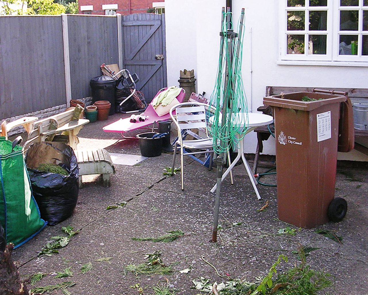 the before shot aof a concrete courtyard with old garden furniture