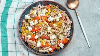 Plate of wholegrain pasta with feta cheese, tomatoes, and herbs