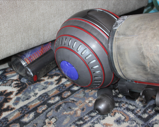 Dyson Ball Animal 3 vacuum cleaner under furniture on a carpeted surface