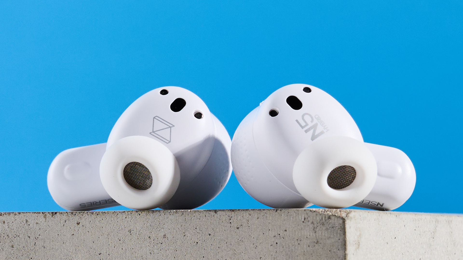 the akg n5 hybrid earbuds by harman in white, shown in their charging case with accessories and without