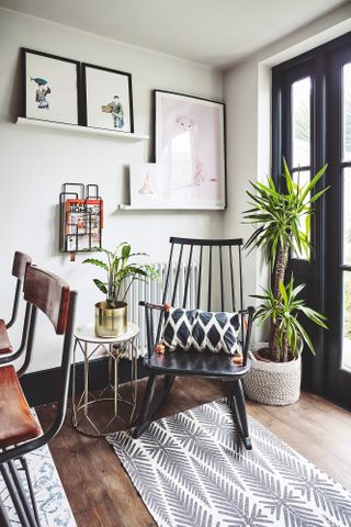 Rocking chair next to the breakfast area with leaf patterned rug, house plants and wall art