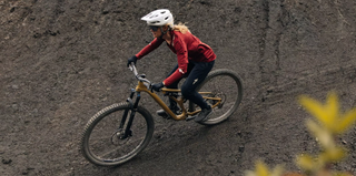 A person on a bike riding along a dirt path on a Specialized bike in Specialized activewear.