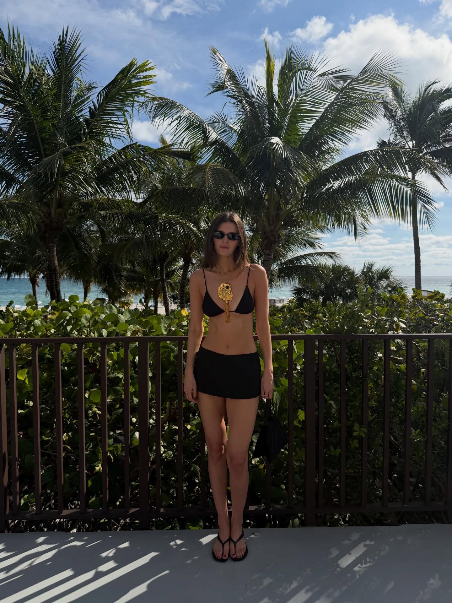Woman wearing a swimsuit and long pendant necklace.